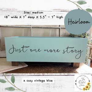 May include: A medium-sized, vintage blue wooden box with the text "Just one more story" in black script. The box is 18 inches wide, 7 inches deep, and 5.5 to 7 inches high. The word "Heirloom" is on a blue circle.