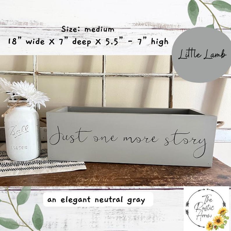 May include: A medium-sized, neutral gray wooden box with the text "Just one more story" in script. The box is 18 inches wide, 7 inches deep, and 5.5 to 7 inches high. A mason jar with flowers is to the left.