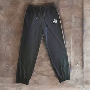 May include: Black sweatpants with a white stripe down each side and a small white square with the text "ok." in the center.