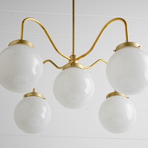 May include: A gold five-light chandelier with white globe-shaped glass shades.