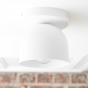May include: A white ceiling light fixture with a round, dome-shaped shade.