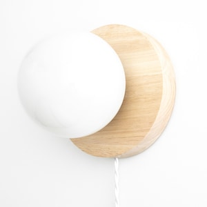 May include: A white globe light fixture mounted on a natural wood half-circle wall plate.