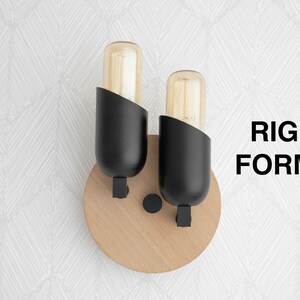 May include: A pair of black wall sconces with wood bases and clear glass bulbs. The sconces are mounted on a white wall with a geometric pattern.