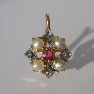 Peut inclure: Boucle d'oreille dorée avec une pierre rose centrale entourée de six perles blanches. Le design comprend des accents argentés et un fermoir à crochet. Bijou probablement vintage ou ancien.