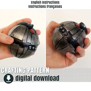 May include: A silver and black sphere with a red button and a pattern of lines and circles. The sphere is being held in a hand. The text "CRAFTING PATTERN digital download" is below the sphere.