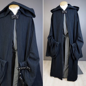 May include: A black hooded robe with a long, flowing design. The robe has large, gathered sleeves and a tie at the waist. The robe is made of a soft, textured fabric.