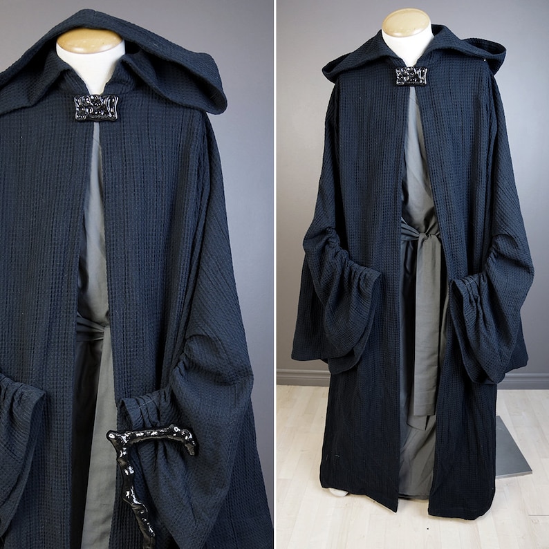 May include: A black hooded robe with a long, flowing design. The robe has large, gathered sleeves and a tie at the waist. The robe is made of a soft, textured fabric.