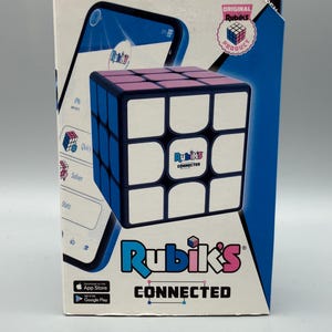May include: A Rubik's Connected puzzle cube in its original packaging. The box features a graphic of the cube, a smartphone screen showing the app interface, and the text "Original Rubik's Product," "Rubik's," and "CONNECTED" with app store logos.