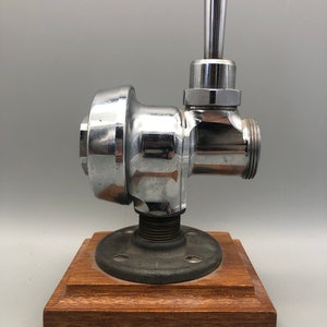 May include: Chrome faucet with a lever handle mounted on a wooden base with a black metal pipe flange.