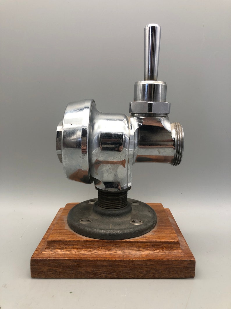 May include: Chrome faucet with a lever handle mounted on a wooden base with a black metal pipe flange.
