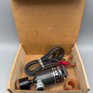 May include: A dark gray cylindrical motor labeled START with a black power cord, two metal alligator clips with red and black rubber covers, and a separate amber-colored plastic ring, all contained within a tan cardboard box with printed text.