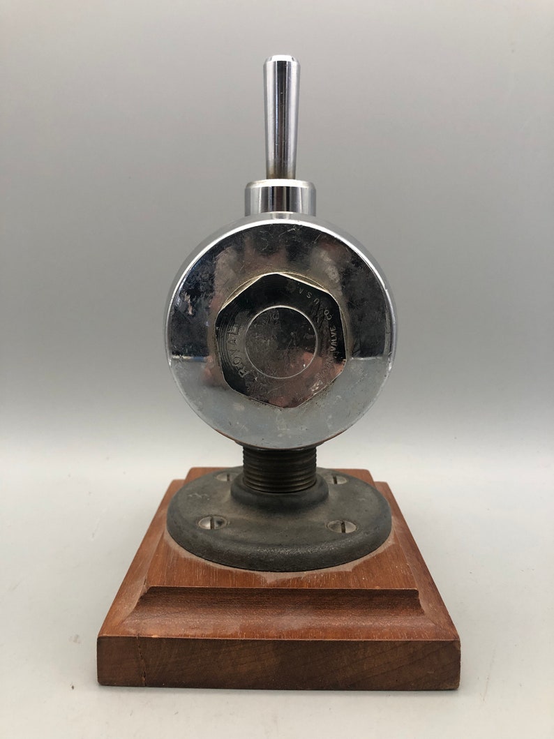 May include: A chrome-plated valve with a wooden base. The valve has a round body with a lever handle and the text "WATER CO.  PAT.  NO.  1,545,010" on the side.