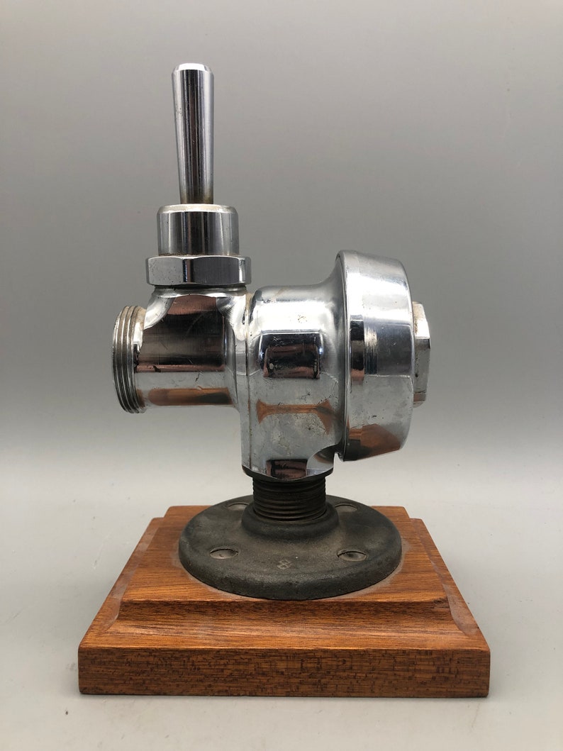May include: A chrome-plated faucet with a wooden base. The faucet has a lever handle and a round body. The base is made of dark wood.