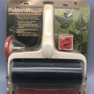May include: A Pattern Magic wallpaper effects kit in its original packaging. The kit includes a white and black roller, a red stamp, and a green stencil with a leaf design. The packaging has text in multiple languages.