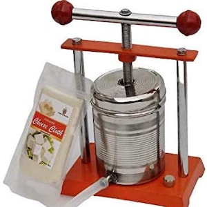May include: A red and orange metal cheese press with a stainless steel container and a clear plastic bag with a white cheese cloth inside. The press has a handle with red knobs and a screw mechanism.