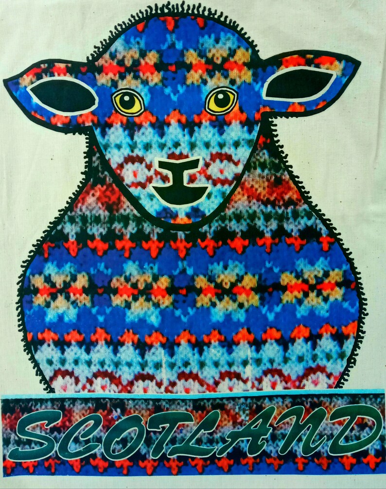 Puede incluir: Una oveja de punto azul, rojo y blanco con contornos negros y ojos amarillos. La oveja est&aacute; de pie sobre un fondo a rayas azul y blanco con la palabra "SCOTLAND" escrita en letras verdes.
