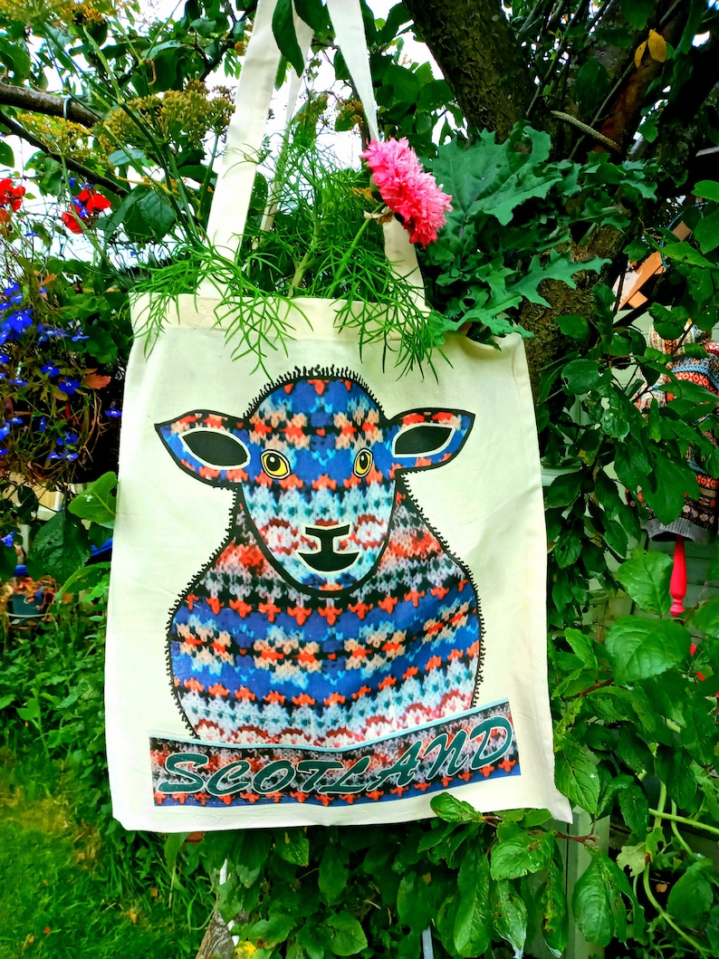 Puede incluir: Una bolsa de lona blanca con una ilustraci&oacute;n de una oveja con estampado azul, rojo y blanco y la palabra "Escocia" impresa en la parte delantera.