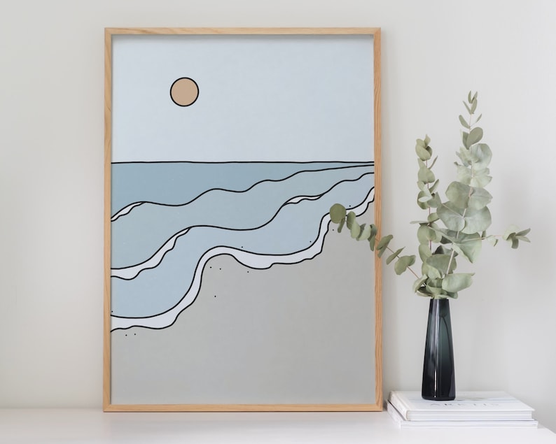May include: A framed print of a minimalist ocean scene with blue waves and a single yellow sun in a light blue sky. The print is on a light gray background.