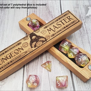 May include: Wooden box with the words "Dungeon Master" engraved on the lid. The box is open and contains a set of seven polyhedral dice. The dice are translucent and have a pink and yellow color scheme.