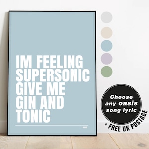 Puede incluir: Un póster enmarcado con un fondo azul claro y texto blanco que dice "IM FEELING SUPERSONIC GIVE ME GIN AND TONIC." Un círculo negro con texto blanco dice "Choose any oasis song lyric." El póster está sobre un suelo de madera.