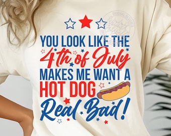 May include: A white t-shirt with a red, white, and blue graphic that says "You look like the 4th of July makes me want a hot dog Real Bad!" with a red, white, and yellow hot dog illustration. The graphic also includes stars.