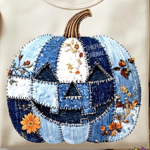 May include: Cream-colored sweatshirt featuring a denim patchwork pumpkin design with a carved face and floral accents. The pumpkin has a brown stem and is embellished with orange and yellow flowers. The text "CHIKIPUM ORIGINAL" is visible on the pumpkin.