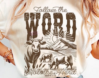 May include: A beige t-shirt with a distressed brown graphic design featuring a cow, mountains, and a sun with a cross. The text "Follow the Word" and "Walk the Herd" is included in the design. The scripture reference "Isaiah 8:11-13" is also included.
