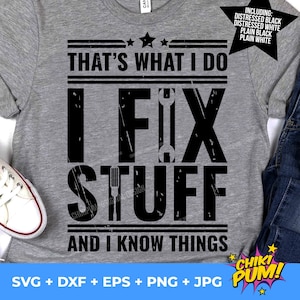Op de afbeelding: Een grijs T-shirt met zwarte tekst die "That's what I do I fix stuff and I know things" luidt. De tekst is in een verweerd lettertype. Het shirt ligt op een witte achtergrond met een paar witte sneakers en een blauwe jeans.