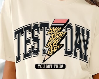 Puede incluir: Una camiseta beige con un gráfico en blanco y negro de un rayo con un diseño de estampado de leopardo. El gráfico dice "Test Day" y "You Got This!"