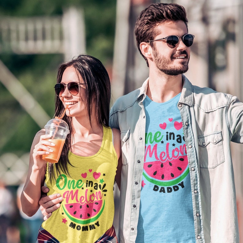 May include: A couple wearing matching watermelon themed tank tops. The woman's tank top says "One in a Melon Mommy" and the man's tank top says "One in a Melon Daddy".