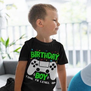 May include: A black t-shirt with a green and white video game controller graphic. The text "Birthday Boy" and "Time to Level Up" are printed on the shirt.
