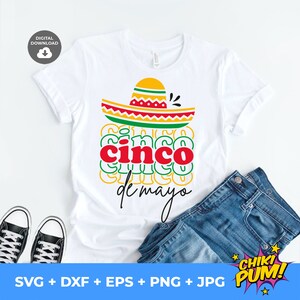 Peut inclure: T-shirt blanc avec un motif color&eacute; pour le Cinco de Mayo. Le motif pr&eacute;sente un sombrero au-dessus des mots "cinco de mayo" en rouge et vert. Le t-shirt est associ&eacute; &agrave; un jean bleu et des baskets noires et blanches.