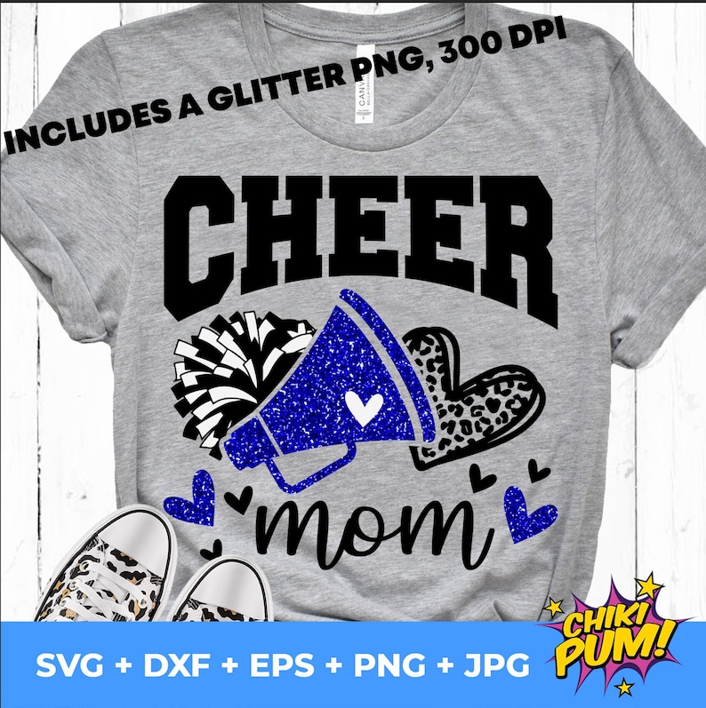May include: A gray t-shirt with the text "CHEER mom" in black and blue glitter. The design includes a blue glitter megaphone with a white heart, a white and black pom-pom, and a leopard print heart.