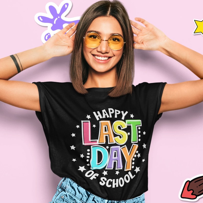 Puede incluir: Una camiseta negra con un gr&aacute;fico colorido que dice "Happy Last Day of School" en un c&iacute;rculo con estrellas blancas.