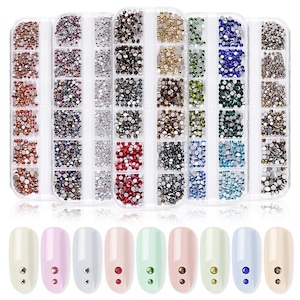 May include: A clear plastic organizer filled with various colors of small, round rhinestones. Below, several painted fingernails each feature a single rhinestone. The rhinestones are in shades of red, silver, gold, and blue.