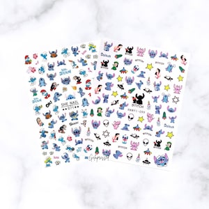 May include: Two sheets of nail art stickers featuring various cartoon character designs. The stickers showcase blue alien-like creatures, stars, and other graphics. The text "Stitch", "She Nail", and "OK!" are visible on the stickers.