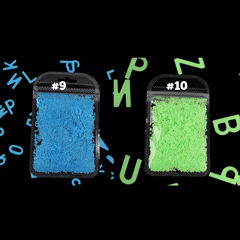May include: Two small, clear plastic bags filled with tiny, curly letters. One bag contains blue letters and is labeled #9. The other bag contains green letters and is labeled #10. The background is black with scattered green and blue letters.