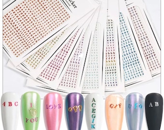 May include: Nail art stickers with various letters and designs. The image shows multiple sheets of small alphabet stickers in different colors, along with several painted nail tips with letters and words like "LOVE" and "GIF".