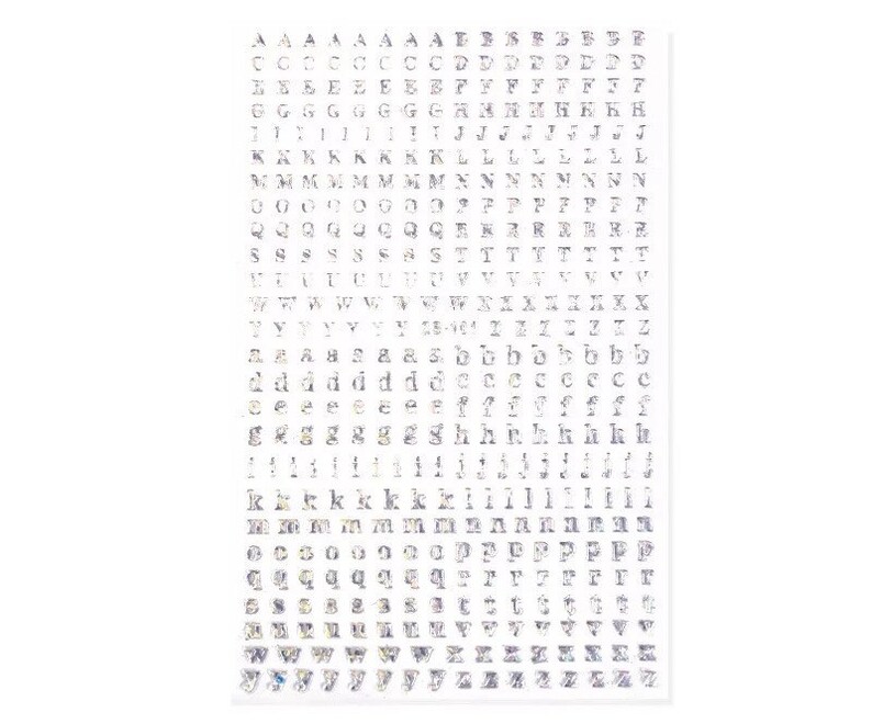 May include: A sheet of clear, adhesive alphabet letters in various fonts. The letters are in a variety of sizes and styles, including uppercase and lowercase. The sheet is rectangular and has a white background.