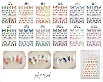 May include: A collection of butterfly nail art stickers in various colors, including blue, orange, and purple. The image also shows examples of the stickers applied to manicured nails, along with a package of the stickers. The brand name "gelapressed" is visible.
