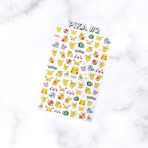 May include: A sheet of nail art stickers featuring various yellow Pikachu designs and other Pok&eacute;mon characters. The sheet is labeled "PIKA #2" in black text. The stickers include different poses and expressions of Pikachu, along with other characters and the Pok&eacute;mon logo.