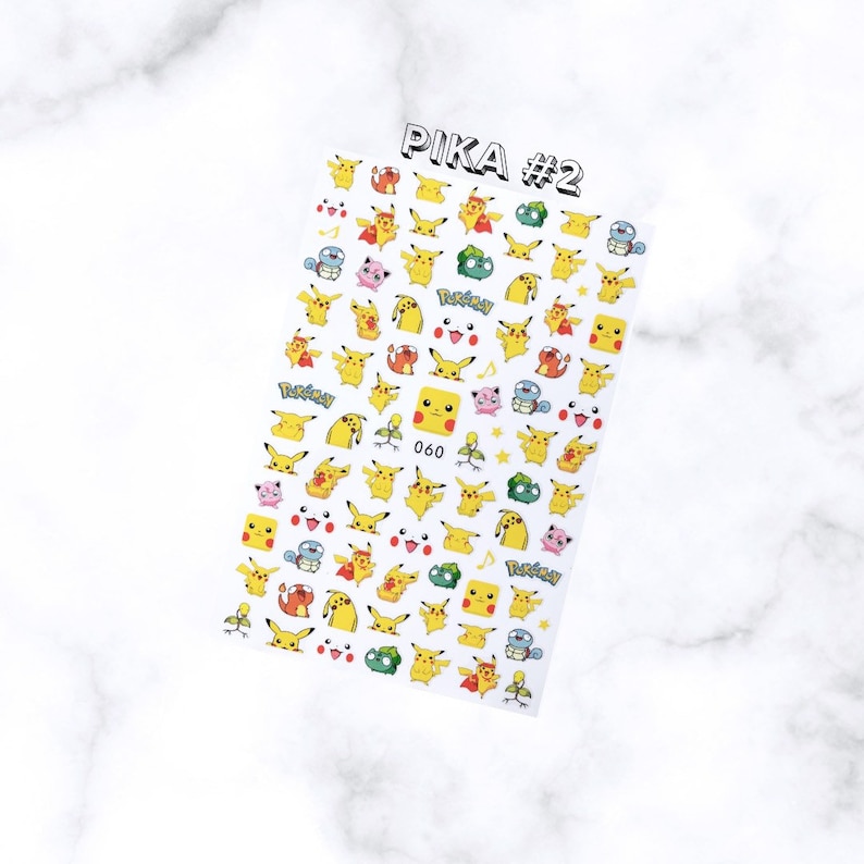 May include: A sheet of nail art stickers featuring various yellow Pikachu designs and other Pok&eacute;mon characters. The sheet is labeled "PIKA #2" in black text. The stickers include different poses and expressions of Pikachu, along with other characters and the Pok&eacute;mon logo.