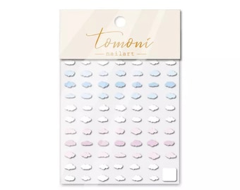 May include: A package of nail art stickers featuring small cloud shapes in shades of white, pink, and blue. The package has the text "tomoni nailart" in gold script.