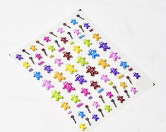 May include: Sheet of colorful nail art stickers featuring gingerbread men, skulls, and stars. The stickers are in various colors including red, yellow, blue, green, and purple. The sheet is on a white background.