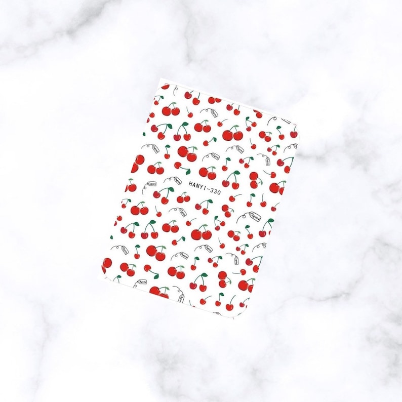 May include: A sheet of nail art stickers featuring a repeating pattern of red cherries with green stems and leaves on a white background. The text "HANYI-330" is visible. The word "Cherry" is also visible.