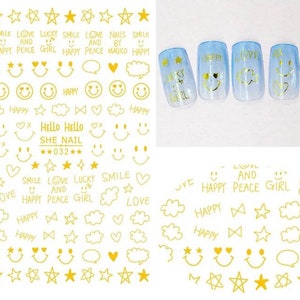 May include: Gold nail art stickers featuring various designs, including stars, smiley faces, hearts, clouds, and text like "LOVE," "SMILE," and "HAPPY." The stickers also include the text "SHE NAIL 032."