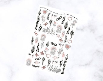 May include: A sheet of nail art stickers featuring various black and red designs. The sheet includes flames, hearts, angels, eyes, roses, and the text "NOT YOURS". The stickers are arranged on a white background.