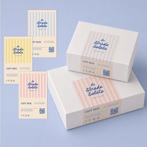 Puede incluir: Dos cajas de regalo rectangulares blancas y tres tarjetas verticales con el logotipo del club de playa La Strada Salata. Los artículos muestran rayas verticales azules, amarillas y rosas, el texto GIFT BOX y un código QR para miembros.