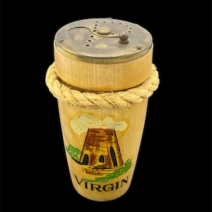 May include: A wooden salt shaker with a brass top and a rope band around the middle. The shaker has a painted image of a building with the word "VIRGIN" below it.