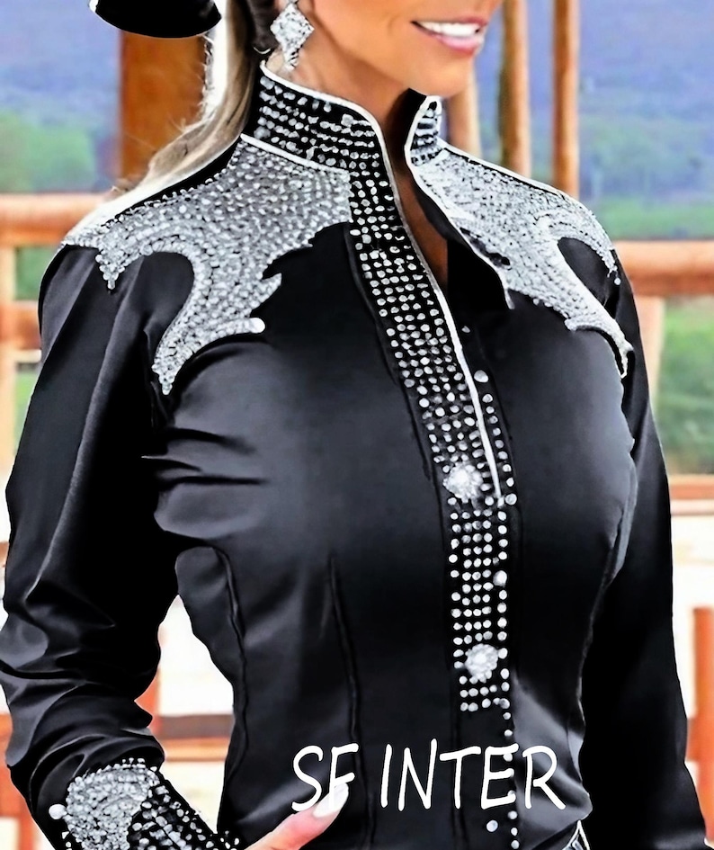 May include: A black long-sleeved shirt with a high collar and a silver rhinestone design. The shirt has a button-up front and a silver rhinestone trim around the collar.